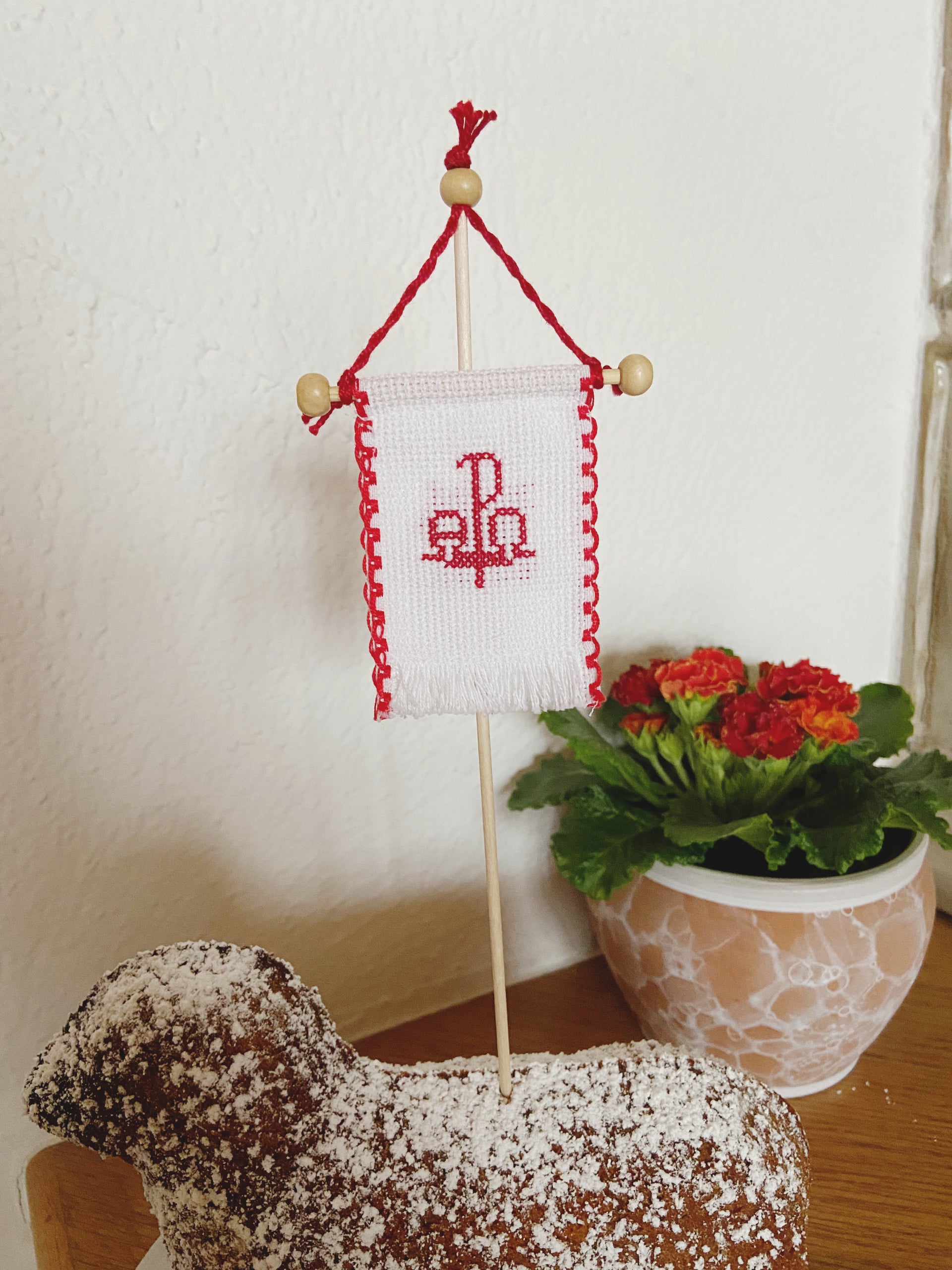 Beidseitig handbesticktes Osterfähnchen mit PAX-Motiv. Die Rückseite zeigt in allen Varianten ein Schaf-Motiv.