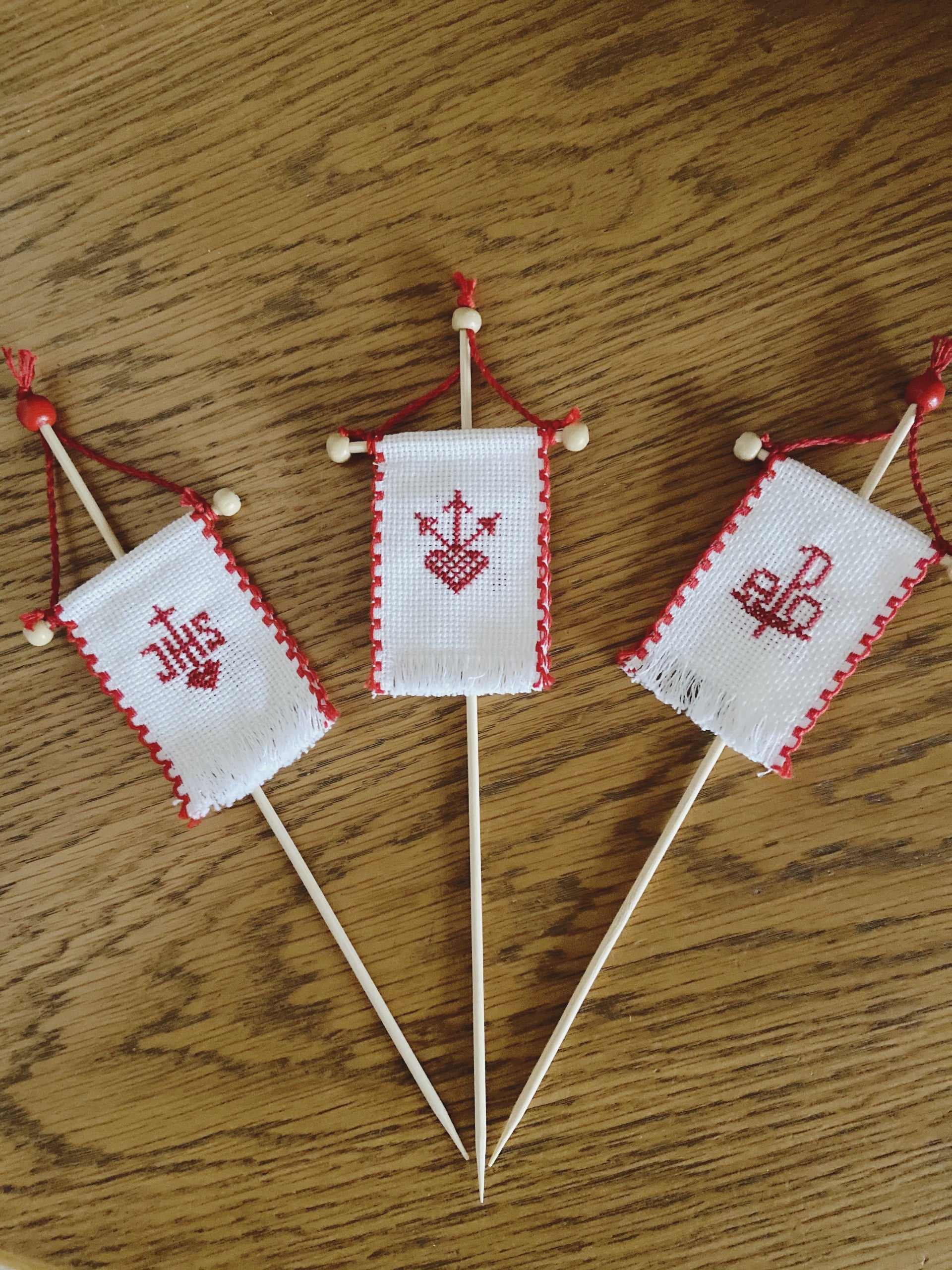 Beidseitig handbestickte Osterfähnchen mit verschiedenen liturgischen Motiven. Die Rückseite zeigt in allen Varianten ein Schaf-Motiv.